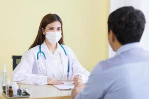Coronavirus protection concept.Asian female doctor Asking patient questions  By wearing a surgical mask at all times photo