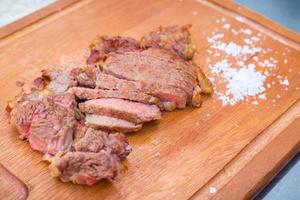 La carne de res medianamente asada, tierna y deliciosamente colocada sobre una tabla de cortar de madera salada al costado es una comida callejera en Tailandia. foto