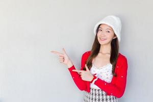 hermosa mujer asiática que usa abrigo rojo y sombrero blanco como una niña santa actúa su mano para presentar algo sobre el fondo blanco. foto