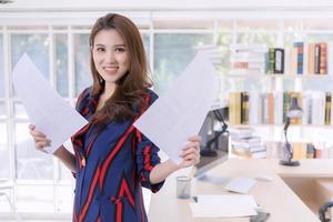 hermosa mujer de negocios asiática sosteniendo documentos en papel mientras trabaja en casa.