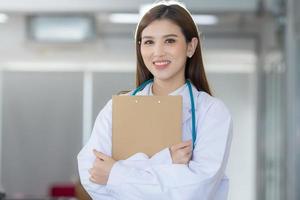 Asian female doctor standing wearing a white robe and stethoscop photo