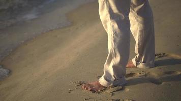 gros plan sur les jambes et les pieds d'une personne qui marche se détend à la plage pendant le coucher du soleil video