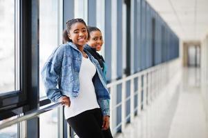 dos amigas africanas con chaqueta de jeans posaron juntas en el interior. foto