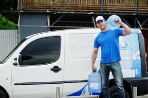 Delivery men in front cargo van delivering bottles of water. photo