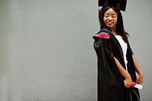 joven estudiante afroamericana con diploma posa al aire libre. foto