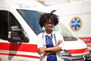 paramédica afroamericana parada frente a un camión de ambulancia. foto