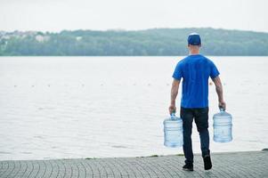 Back of delivery man with water bottles at hands. photo