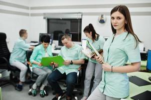 Medical theme .Portrait of female doctor with clipboard against group of doctors meeting in the mri office at diagnostic center in hospital. photo