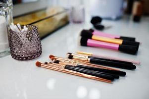 Makeup brushes on white gloss table on make up saloon. photo