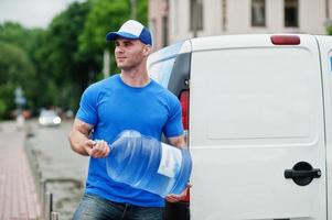 Delivery men in front cargo van delivering bottles of water. photo