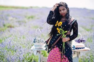 hermosa niña india usa vestido tradicional saree india en campo de lavanda púrpura. foto