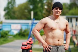 Man arabian sport man torso with hat doing exercises on bars. photo