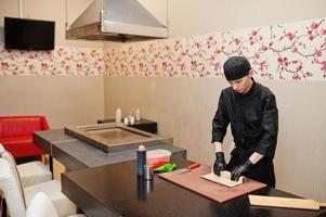 Professional chef wear in black making sushi and rolls in a restaurant kitchen of japanese traditional food. photo