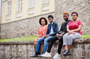 cuatro amigos africanos divirtiéndose al aire libre. dos chicas negras con chicos se sientan en una ciudad vieja. foto