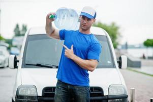 Delivery man in front cargo van delivering bottles of water showing finger. photo