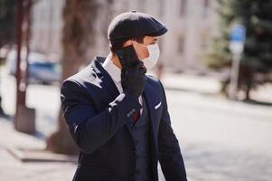 Concept of coronavirus quarantine. Business man wear on suit and cap with medical face mask, speak on phone. MERS-Cov, Novel coronavirus 2019-nCoV photo