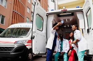 Group of african paramedic ambulance emergency crew doctors making selfie on phone. photo