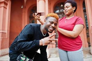 African friend couple having fun outdoor. Girlfriend combs her boyfriend photo