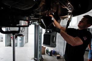 Car repair and maintenance theme. Mechanic in uniform working in auto service. photo