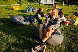 Young multi ethnic group of people watching movie at poof in open air cinema. Close up portrait of funny guy. photo