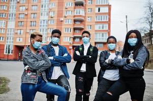 Group of african teenagers friends against empty street with building wearing medical masks protect from infections and diseases coronavirus virus quarantine. photo