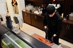 Professional chef wear in black making sushi and rolls in a restaurant kitchen of japanese traditional food. photo