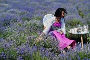 Beautiful indian girl wear saree india traditional dress sitting in purple lavender field with decor. photo