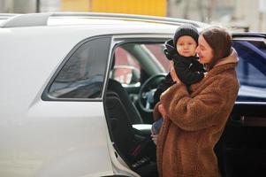 la joven madre y el niño se paran cerca de su auto todoterreno. concepto de conducción segura. foto