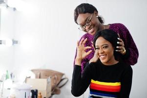 mujer afroamericana aplicando maquillaje por maquillador en el salón de belleza. foto