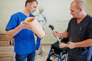 Two prosthetist man workers with prosthetic leg working in laboratory. photo