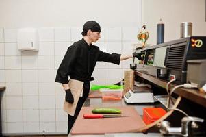 Professional chef wear in black making sushi and rolls in a restaurant kitchen of japanese traditional food. photo