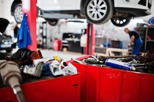 tema de reparación y mantenimiento de automóviles. mecánico en uniforme que trabaja en el servicio de automóviles. foto