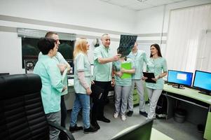 Medical theme.Observation room with a computer tomograph. The group of doctors meeting in the mri office and looking at x-ray at diagnostic center in hospital. photo