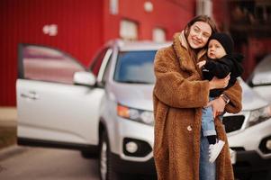 Young mother and child stand near they suv car. Safety driving concept. photo