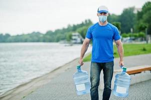 Delivery water man wear protective face medical mask during coronavirus pandemia. photo