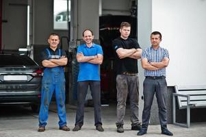 Car repair and maintenance theme. Three mechanic and manager in uniform in auto service. photo