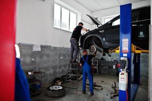 Car repair and maintenance theme. Mechanic in uniform working in auto service. photo