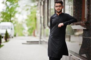 Pakistano bangladesh man wear black traditional clothes and eyeglasses pose outdoor. photo