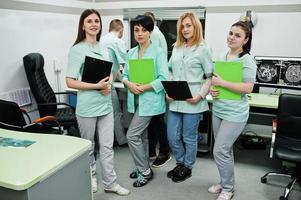 Medical theme.Observation room with a computer tomograph. The group of female doctors with clipboards meeting in the mri office at diagnostic center in hospital. photo