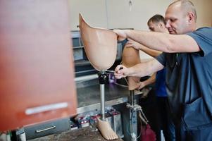 Two prosthetist man workers making prosthetic leg while working in laboratory. photo