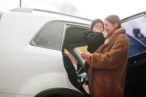 Young mother and child stand near they suv car. Safety driving concept. photo