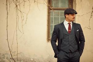 Portrait of retro 1920s english arabian business man wearing dark suit, tie and flat cap. photo