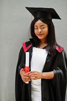 Young female african american student with diploma poses outdoors. photo