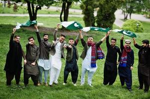 grupo de hombres paquistaníes vestidos con ropa tradicional salwar kameez o kurta con banderas de pakistán. foto