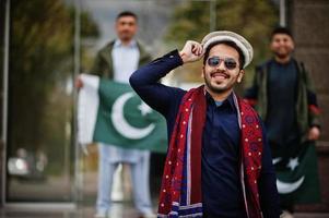 grupo de hombres paquistaníes vestidos con ropa tradicional salwar kameez o kurta con banderas de pakistán. foto