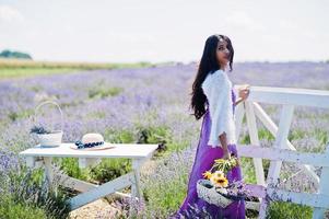 hermosa niña india usa vestido tradicional saree india en campo de lavanda púrpura. foto