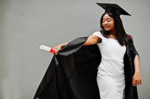 joven estudiante afroamericana con diploma posa al aire libre. foto
