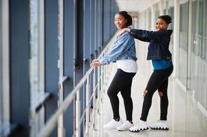 Two african woman friends in jeans jacket posed indoor together. photo