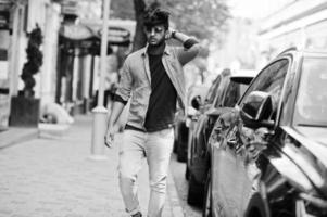 Portrait of young stylish indian man model pose in street in sunglasses against car. photo