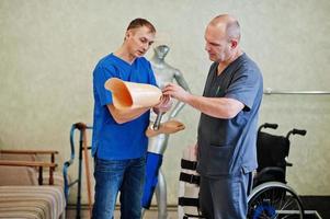 Two prosthetist man workers with prosthetic leg working in laboratory. photo